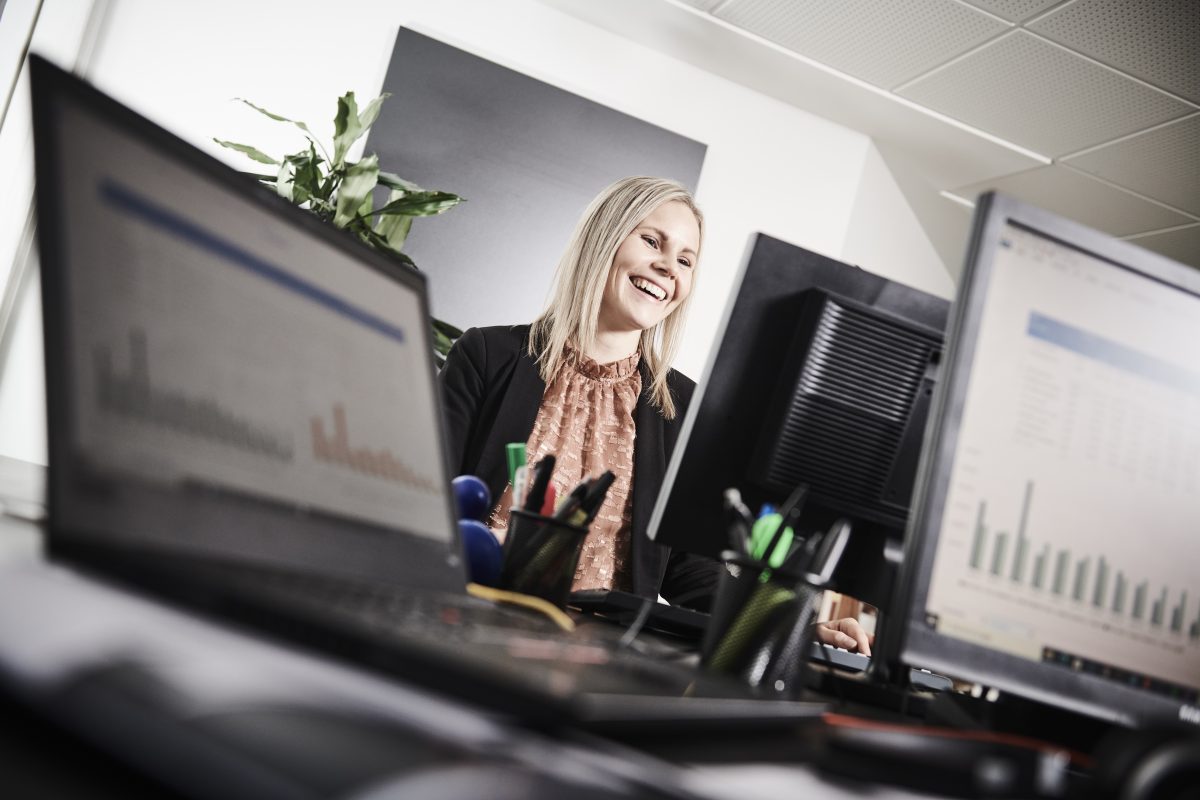 En kvinde, der kigger på en computerskærm og smiler